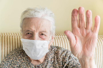 Old woman with health mask making stop sign with wrinkled hand