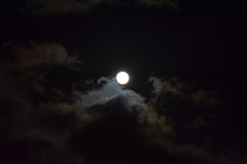 Fototapeta na wymiar A full moon with clouds in the black night sky. Full moon on January 31, 2018. A supermoon. Beautiful clouds in the night sky. Natural mysterious background. Space. Bright light from the moon