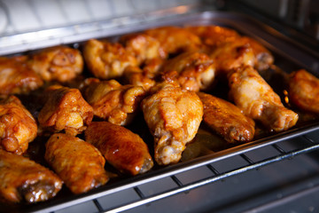 Chicken wings baked on a stainless steel tray in the microwave.