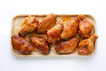 Baked chicken wings in a wooden plate on a white table