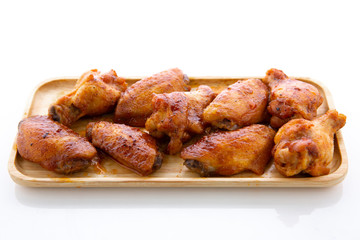 Baked chicken wings in a wooden plate on a white table