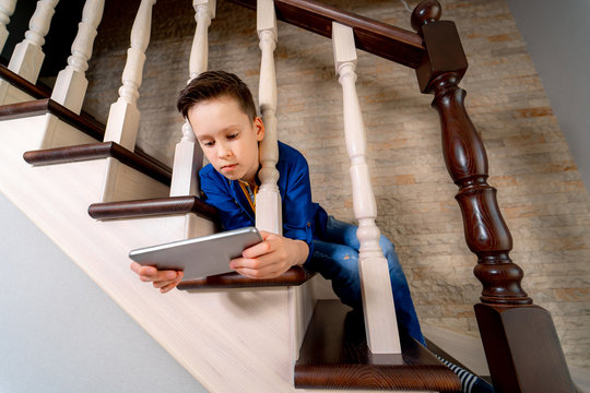 Teenage With Tablet On Stairs. View From Below.