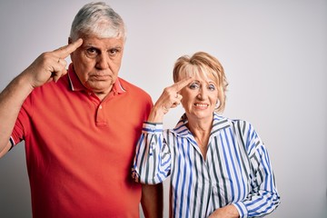 Senior beautiful couple standing together over isolated white background Shooting and killing oneself pointing hand and fingers to head like gun, suicide gesture.