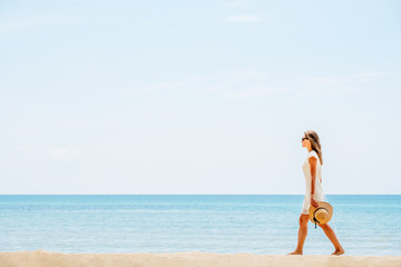 Beautiful woman in a white dress walking on the beach