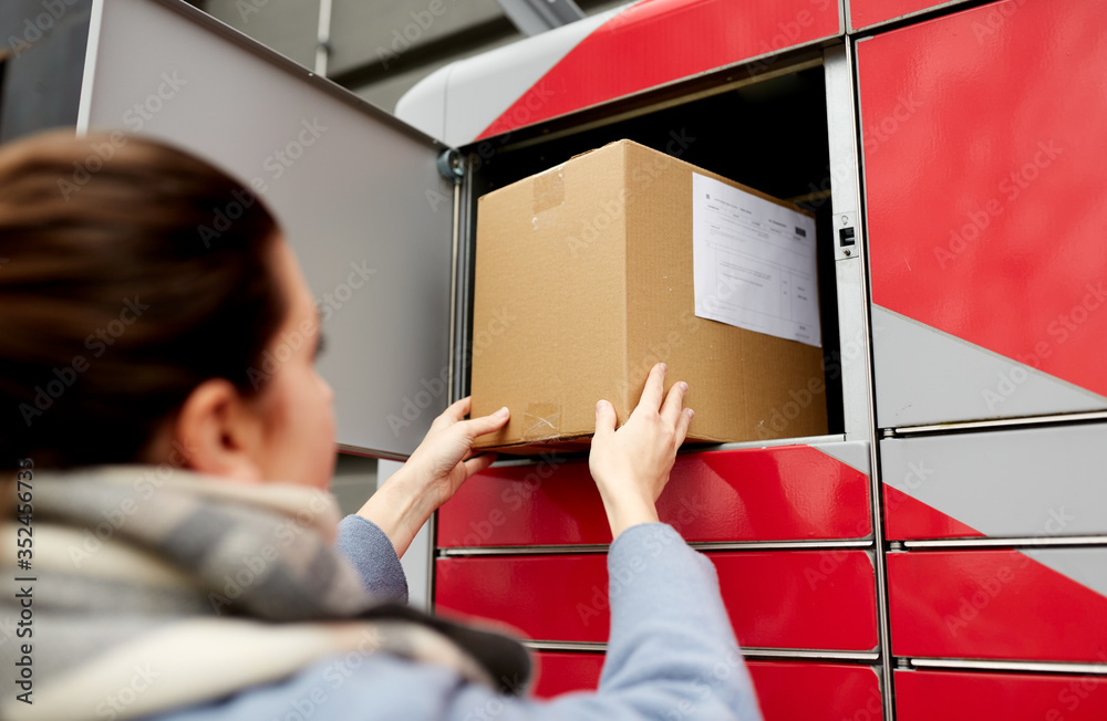 Wall mural mail delivery and post service concept - woman putting box to automated parcel machine