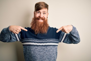Handsome Irish redhead man with beard wearing winter sweater over isolated background looking...