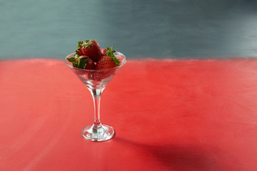 Red sweet ripe strawberries in glass on red background. Healthy organic sweet fruit.