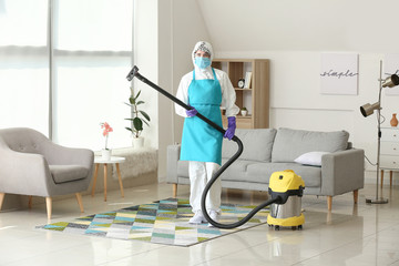 Fototapeta na wymiar Housewife in protective costume cleaning floor in room