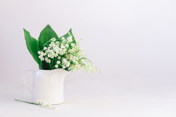 Romantic bouquet of the lilies of the valley in a jar on a white background.
