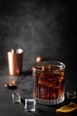 Glass of cold cola with ice cubes on dark background