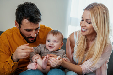 Loving parents with their cute baby playing on bed.