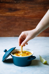 A woman's hand with a bread spike that she will dip into a dish of delicious hummus with olive oil and paprika. Next to it there are pieces of lemon.