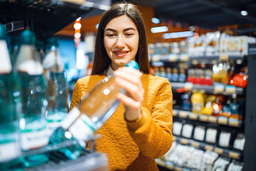 Woman choosing mineral water in grocery store