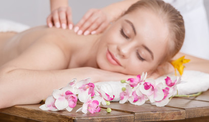 Fototapeta na wymiar Pleasure of spa treatments. Female hands do relaxing massage for woman with closed eyes