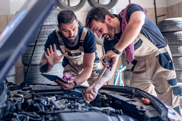 Two mechanics in uniform are working in auto service.