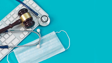 shot brown gavel, medical stethoscope and mask, computer keyboard. technology concept in medicine on a blue background. free copy space for text. close up top view