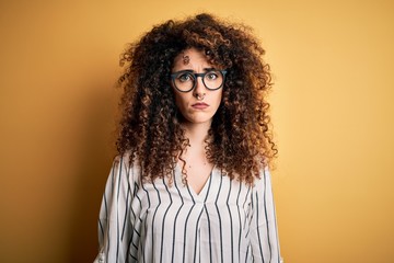 Young beautiful woman with curly hair and piercing wearing striped shirt and glasses depressed and worry for distress, crying angry and afraid. Sad expression.