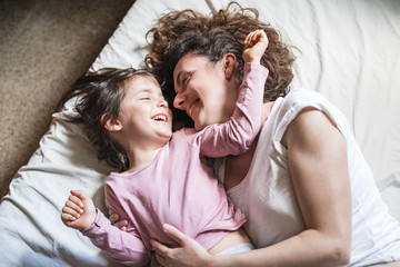 Mother and child look at each other in bed smiling