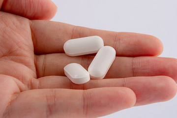 Woman holding out hand full of pills, close-up on hand