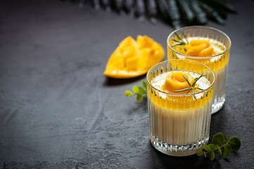 Italian dessert panna cotta with mango in glass over dark background