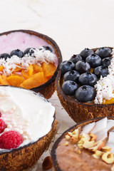 exotic smoothie bowls with berries in coconut bowls on white background, trendy dessert