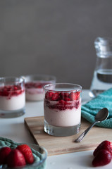 Tasty Italian dessert panna cotta or strawberry mousse in glass in the kitchen. Delicious panna-cotta with fresh red berries. Bright healthy cheesecake