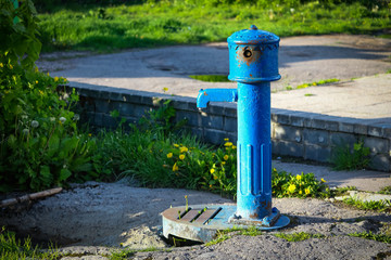 Blue water pump sanding in yard with greenery