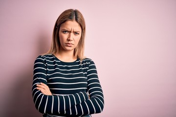 Young beautiful blonde woman wearing casual striped sweater over pink isolated background skeptic...