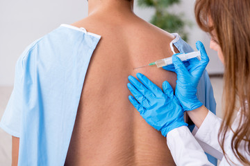 Young back injured man visiting female doctor chiropractor