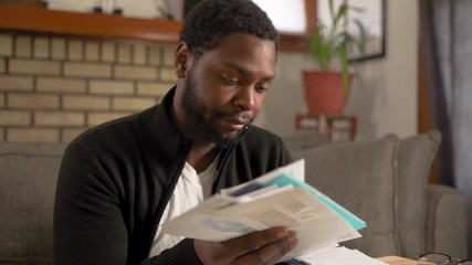 Black man tosses junk mail tired unconcerned close up