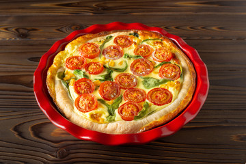 Vegetable pie called Quiche on a wooden background