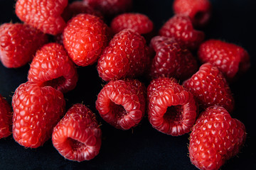 Red fresh raspberries on black background