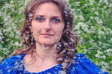 Young woman with falling dandelion seeds (umbrellas)