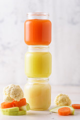 natural vegetable baby food in glass jars with zucchini, cauliflower, carrots on white background, child nutrition