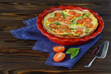 Vegetable pie called Quiche on a wooden background