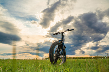Fototapeta na wymiar A Bicycle with thick wheels on a green meadow against a beautiful sky.