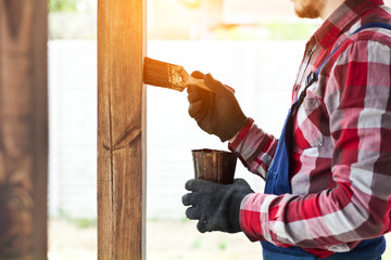 The worker is painting the wooden terrace