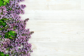 Dorder of lilac flowers on light wooden background. Top view, flat lay, copy space. S
