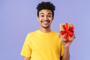 Photo of happy african american man holding gift box and smiling