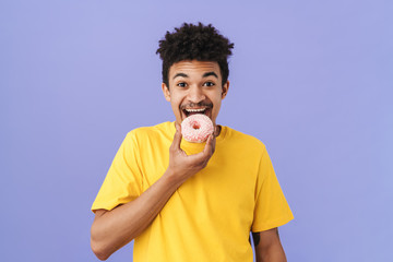 Photo of cheerful african american man eating donut and smiling