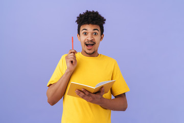 Photo of surprised african american man holding pen and exercise book