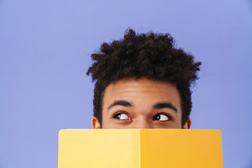 Photo of african american man covering his face with exercise book