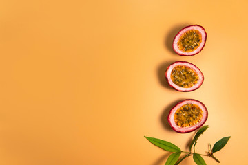 Top down view Cut half passion fruit (maracuja) decorate with branch of plant and green leaves on plain yellow orange color background and copy space.