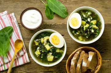 Green soup with sorrel, eggs and potatoes on a wooden background