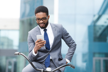 Handsome businessman texting on phone sitting on bike