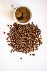 Top view of black coffee in white cup, with roasted fresh beans around. Coffee cup and coffee beans on white background. Black coffee in a coffee cup top view isolated on white background.