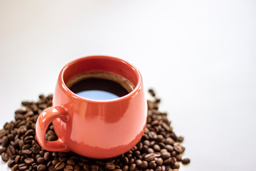 Pink coffee cup and beans on a white background. Side view of pink cup of coffee with beans on white table. Space for text. Close up.