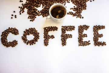 Cup of black coffee on white background with letter coffee wrote from fresh rosted beans. White cup of coffee and letters Coffee. Brown coffee letters isolated on a white background. Copy-space.