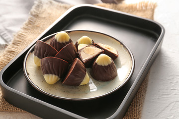 Plate with tasty chocolate candies on white background