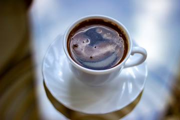 Black coffee in white cup on glass table. Bird eyes view of coffee cup on tea table. Top view of cup of hot coffee in white cup.